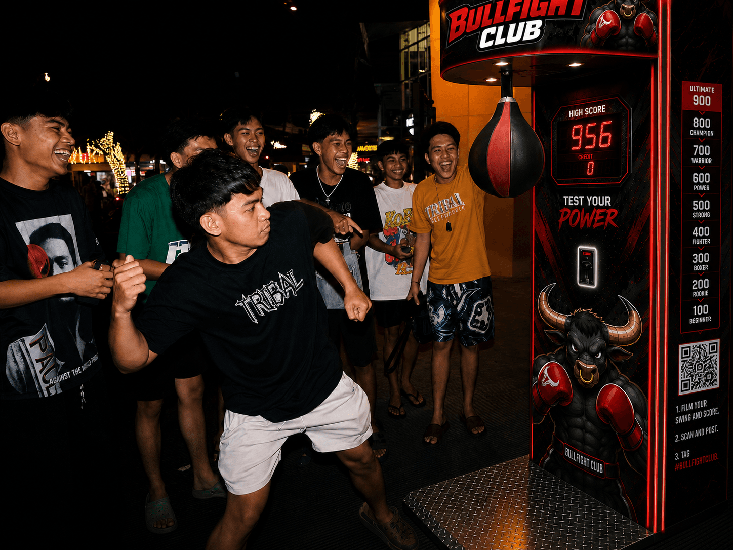 A crowd cheering as someone punches the Bullfight Club machine at night